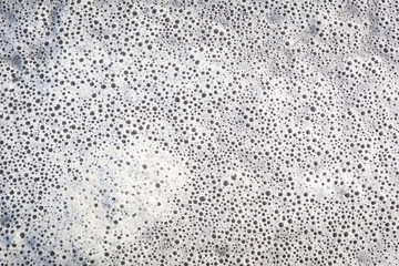 Carpet of foamy swimming Bubbles / Background texture of many small foam bubbles at water surface