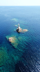 Aerial drone bird's eye view of iconic lighthouse of Tourlitis in port of Andros island chora,...
