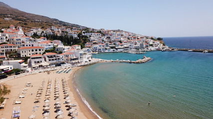 Aerial drone bird's eye view of picturesque village of Batsi with traditional taverns and clear water beach, Andros island, Cyclades, Greece