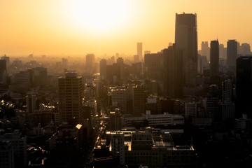 Aerial view of a city skyline at sunset with haze