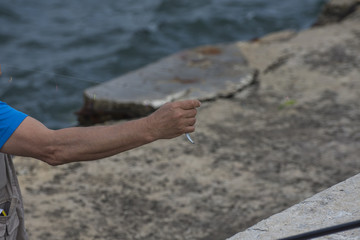 Fish on a hook. Fisherman holding a string with hooked fish. Copy space, selective focus.