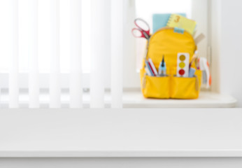 White table over blurred background of school backpack on window