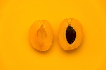 Two halves of apricot on a yellow background. Cut into half-and-half apricot.