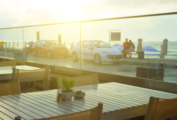 Magical sunset from a restaurant by the sea with walking people and parked cars. Depth of field focus blur. Crete, Greece
