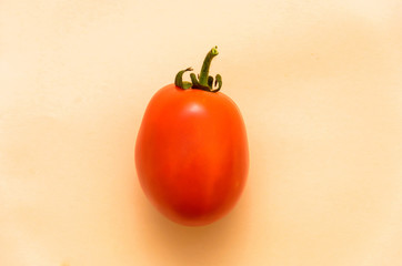One bright juicy red tomato on a beige background.