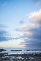 scenic landscape in early morning sunrsie for ocean rocks beach and waves for young surfers on the background. blue beautiful sky with sweet clouds. blue hours  and magic colours