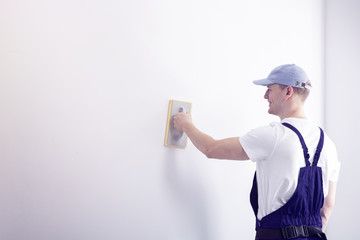 Professional worker with blue cap smoothing white wall with copy space