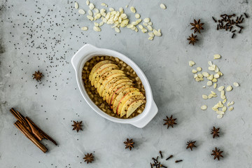 Top view on dessert with apples and cloves and cinnamon on grey background
