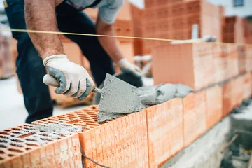 Fotobehang Professional worker using pan knife for building brick walls with cement and mortar © aboutmomentsimages