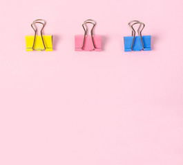 Colorful binder clips on pink background.
