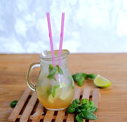 Cold summer drink, lemonade with lime and basil on the basis of sparkling water and sugar syrup in...