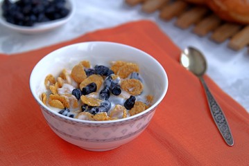 Summer breakfast, natural yoghurt with cornflakes and berries of edible honeysuckle