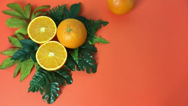 Sobre fondo naranja, naranjas sobre hojas y aparece otra rodando.