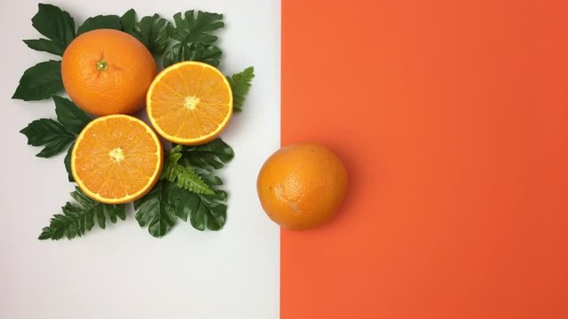 Escena de naranjas sobre hojas, aparece otra rodando sobre fondo naranja y blanco.