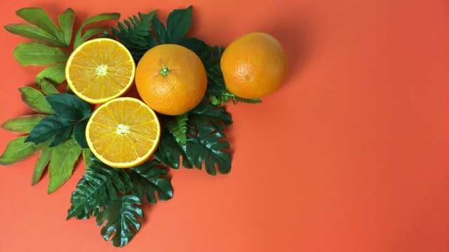 Escena de naranjas sobre hojas, aparece una rodando.
