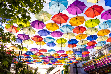 Fototapeta na wymiar Colorful umbrellas background. Multi-colored umbrellas in the sky. Street decoration.