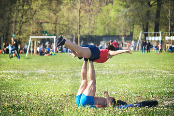Fit couple doing acroyoga, Healthy Lifestyle in the park with defocused people on the background
