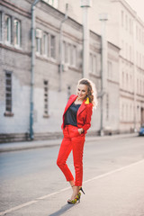 Portrait of a beautiful bright girl street style lifestyle smiling and posing in a red suit on a sunny day