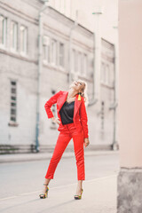 Portrait of a beautiful bright girl street style lifestyle smiling and posing in a red suit on a sunny day