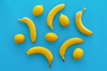yellow bananas and lemons on bright blue paper, trendy flat lay. fruits modern image, top view. juicy summer vitamin abstract background. pop art style. minimalism pattern