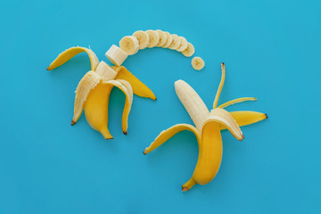slices of banana on bright blue paper, trendy fruit modern flat lay. juicy  vitamin abstract background. time to eat and diet concept. pop art style. open and sliced banana pattern