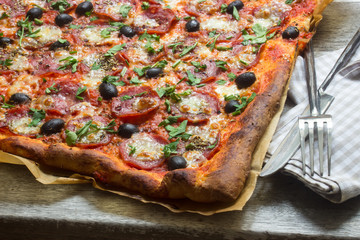 Pizza mit Salami und Oliven im Ganzen mit Besteck