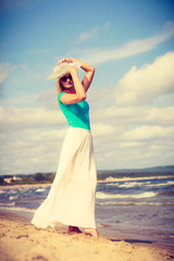 Fototapeta na wymiar Blonde woman wearing dress walking on beach
