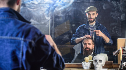 Man with beard and mustache in hairdressers chair in front of mirror background. Reflexion of...