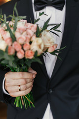 groom holding stylish bouquet with roses and eucalyptus. morning preparations before wedding day. groom waiting for his bride