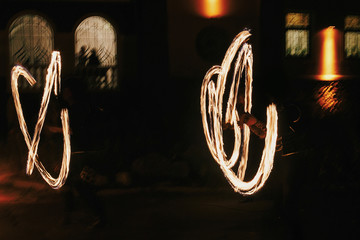 Fire dancers swing, spinning fire and man juggling with bright sparks in the night. fire show...