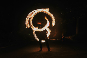 amazing fire show at night at festival or wedding party. Fire dancers swing, spinning fire and man...
