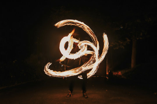 amazing fire show at night at festival or wedding party. Fire dancers swing, spinning fire and man juggling with bright sparks in the night. fire show performance and entertainment