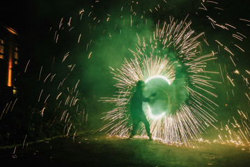 Fire dancers swing, spinning green fire and man juggling with bright sparks in the night. fire show performance and entertainment. amazing fire show at night at festival or wedding party