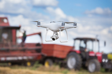 Obraz na płótnie Canvas Drone in front of tractor and combine harvester in field