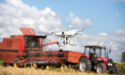Fototapeta na wymiar Drone in front of tractor and combine harvester in field