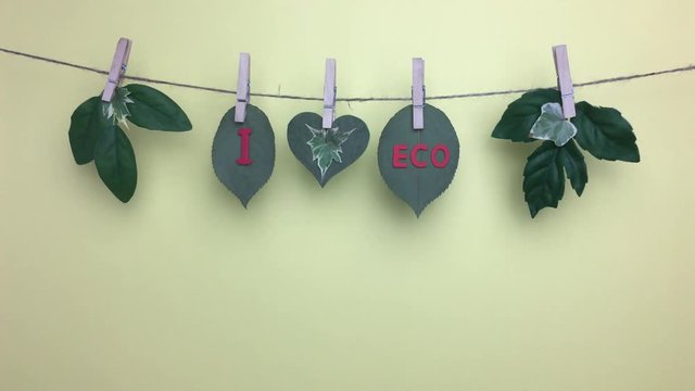 Frase &ldquo;I love eco&rdquo; en una cuerda con pinzas sobre fondo amarillo.