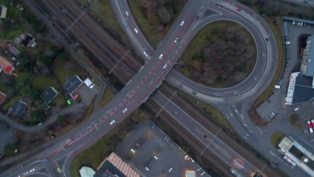 Aerial top down view of interchange road junction and railway train station. Spinning drone shot flying up over crossing roads and railway track. 4K resolution