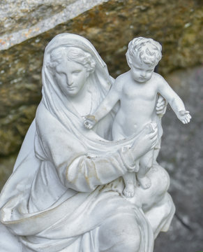 White stone statue of the virgin Mary carrying a baby