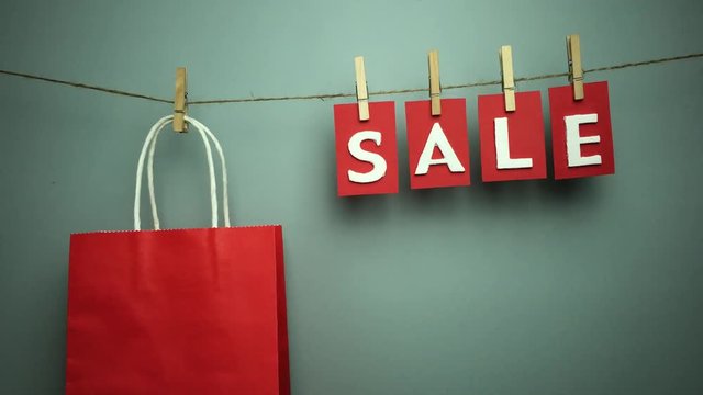 Palabra &ldquo;sale&rdquo; y bolsa de papel colgando de una cuerda con pinzas.