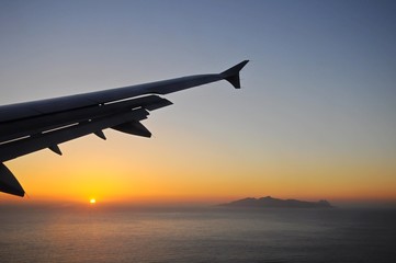 Viewing sunrise above sea on a flying plane toward Santorini Island in Greece