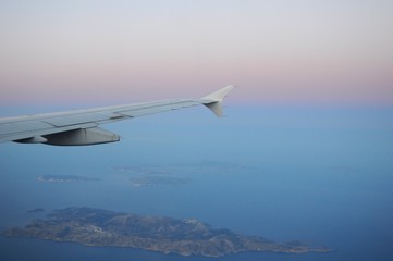 Naklejka na ściany i meble Viewing sunrise above sea on a flying plane toward Santorini Island in Greece