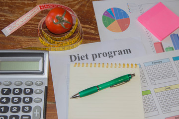 Healthy natural organic food diet. calculator, notepad and centimeter on a wooden table