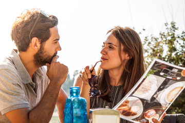 Happy couple sitting at bar table ouside in rome reading breakfast menu deciding if cappuccino, coffee or cornetto