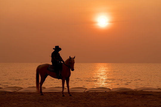 Horse riding on the beach at sunset