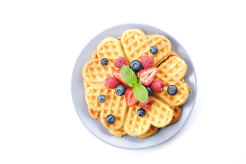 Festive breakfast composition with homemade waffles and variety of different summer berries and mint leaves.