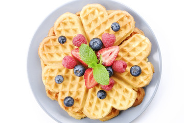 Festive breakfast composition with homemade waffles and variety of different summer berries and mint leaves.