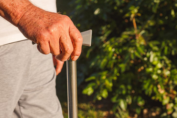 Senior man hands holding stick close up.