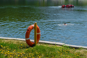 a life preserver on the shore of the lake in the background swimming people