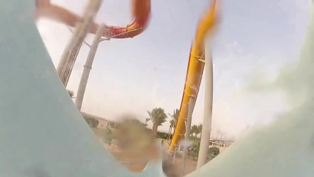 Wonderful 4k first person pov shot of male sliding down extreme hydro water slide tube in big swimming pool aquapark