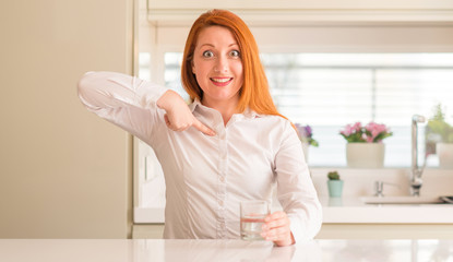 Thirsty redhead woman and glass of water with surprise face pointing finger to himself